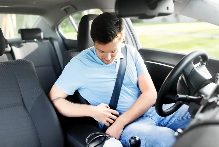 Occupant fastening a seat belt in a vehicle before a journey.
