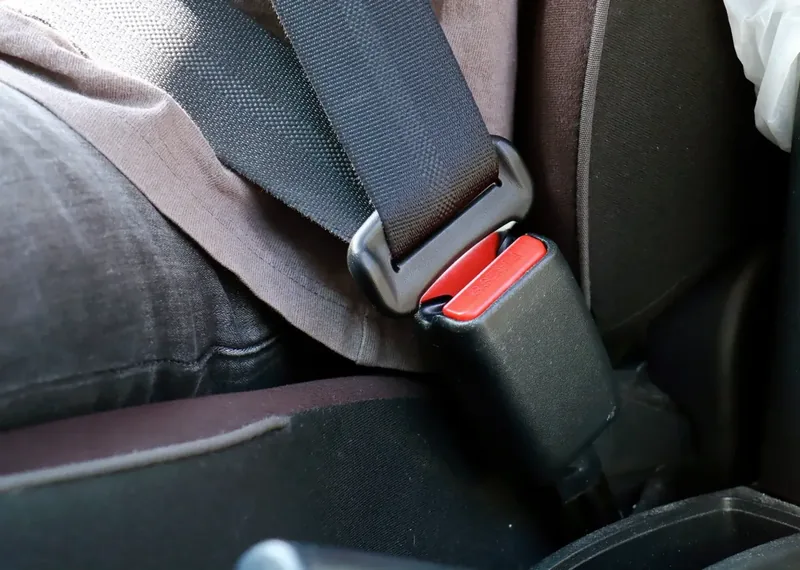 Seat belt fastened across a seated occupant in a car, buckle and latch plate engaged.